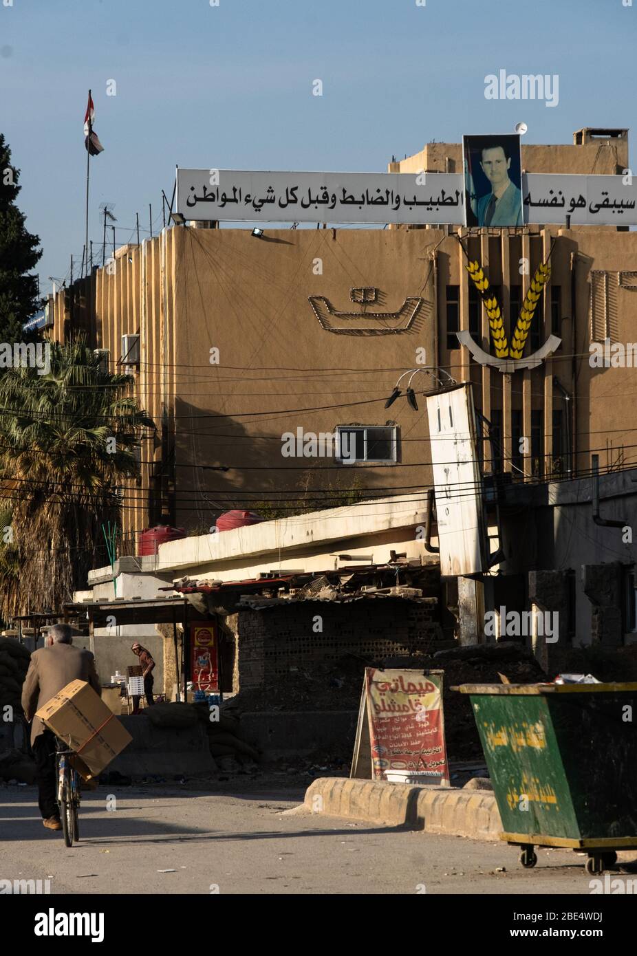 Un locale passa davanti a un ritratto di Bashar al-Assad a Qamishli, Siria. Foto Stock