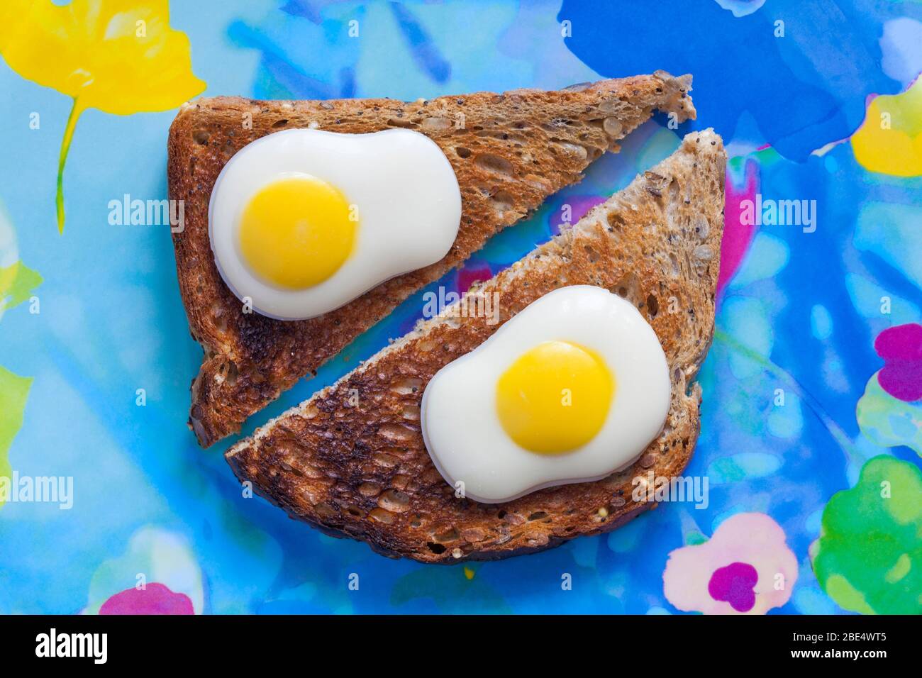 M&S uova fritte decorate con cioccolato bianco solido pronto per Pasqua, con toast su piatto colorato - uova su toast - uova su toast Concept - uova da colazione Foto Stock