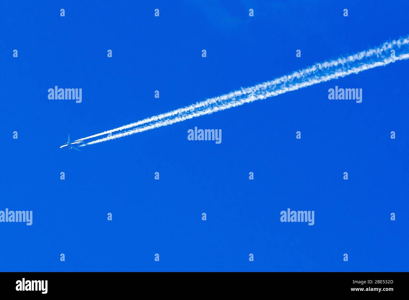 Una linea di jet doppia con motore Delta Airlines lascia un sentiero di vapore contro un cielo blu. Foto Stock