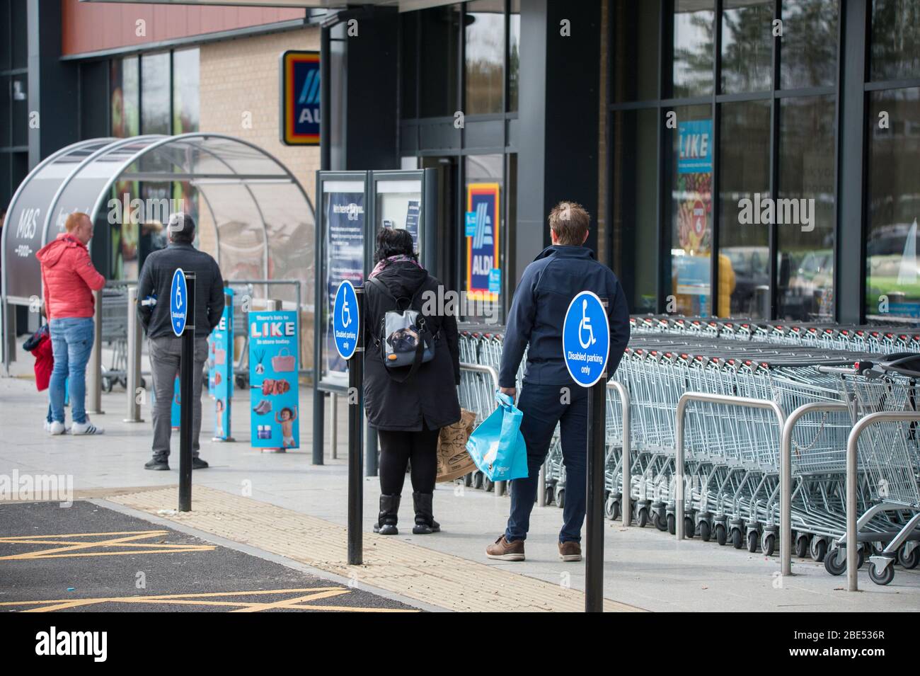 Cumbernauld, Regno Unito. 12 aprile 2019. Nella foto: I clienti si accodano fuori da un negozio mantenendo le distanze sociali. Scene durante il blocco di Coronavirus (COVID-19) da un parco al dettaglio in Cumbernauld. Gli acquirenti si accodano fuori per ottenere le loro offerte e forniture per il periodo festivo della Domenica di Pasqua. Credit: Colin Fisher/Alamy Live News Foto Stock