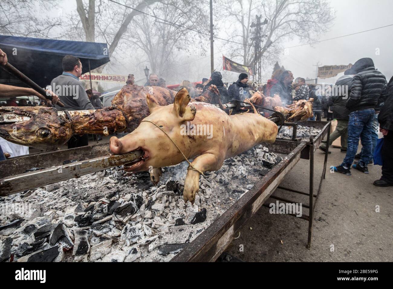 KACAREVO, SERBIA - 18 FEBBRAIO 2017: Uomo Roasting un maiale e un agnello, su una griglia tradizionale della Serbia, nei Balcani, chiamato Pecenje su un mercato. Por Foto Stock