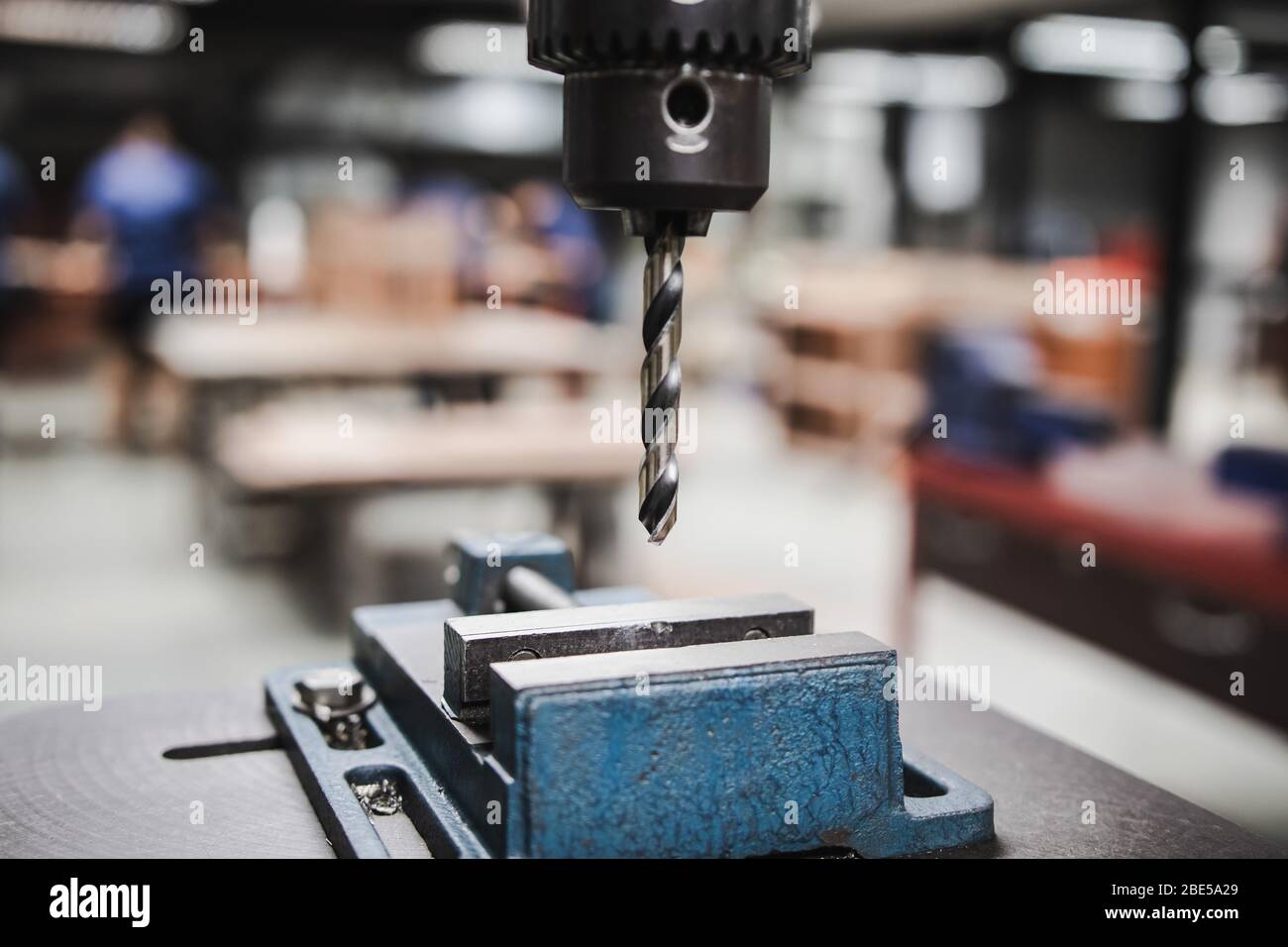 Metallo industriale della punta di perforazione in officina camera con sfondo sfocato di studenti di lavorare su altri progetti di officina Foto Stock