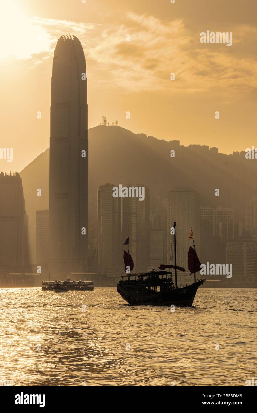 Vecchia nave a vela e urban skyline con moderni grattacieli di Hong Kong al tramonto Foto Stock