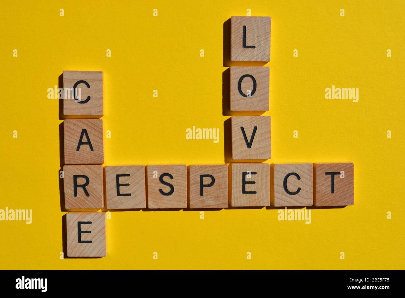 Amore, cura, rispetto, parola chiave in lettere alfabetiche in legno 3d su giallo Foto Stock