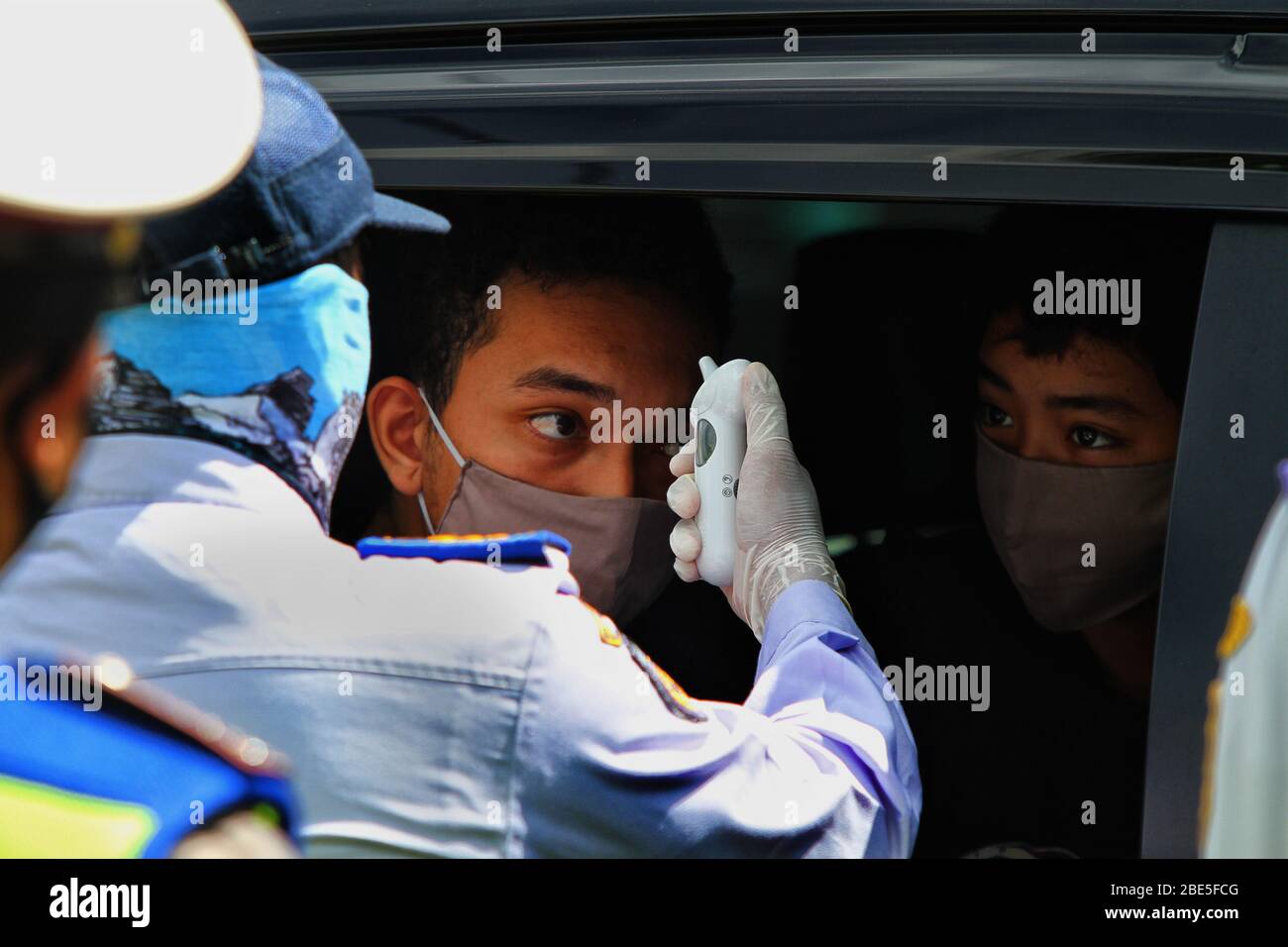 Yogyakarta, Indonesia. 12 aprile 2020. Funzionari dell'Agenzia indonesiana dei trasporti controllano la temperatura corporea dei residenti durante l'operazione di manipolazione del virus corona al confine con Yogyakarta, Indonesia, domenica 12 aprile 2020. Le operazioni frontaliere sono effettuate per limitare lo spazio per i residenti durante le operazioni di distanziamento fisico. (Foto di Devi Rahman/INA Photo Agency/Sipa USA) Credit: Sipa USA/Alamy Live News Foto Stock