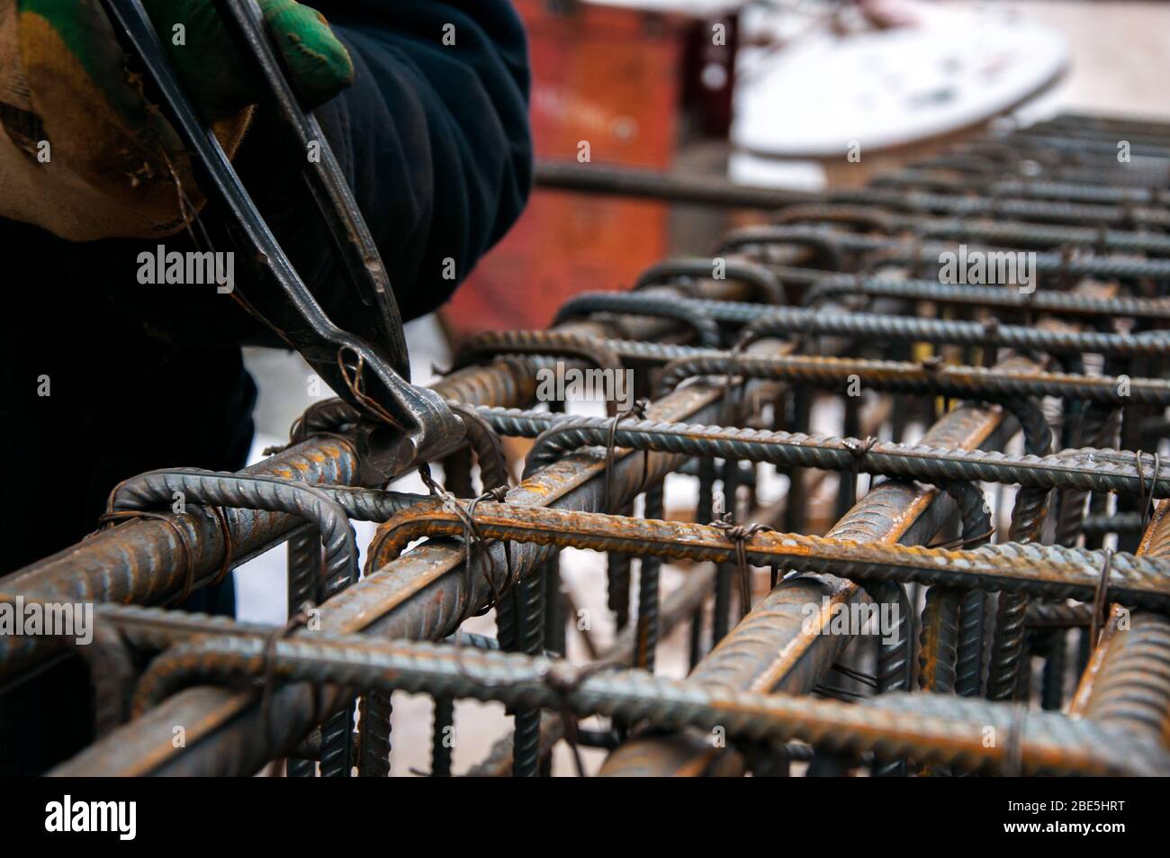 Fissaggio delle barre di riposizionamento l'una all'altra. Le mani del lavoratore fissano il rinforzo con il filo. Foto Stock