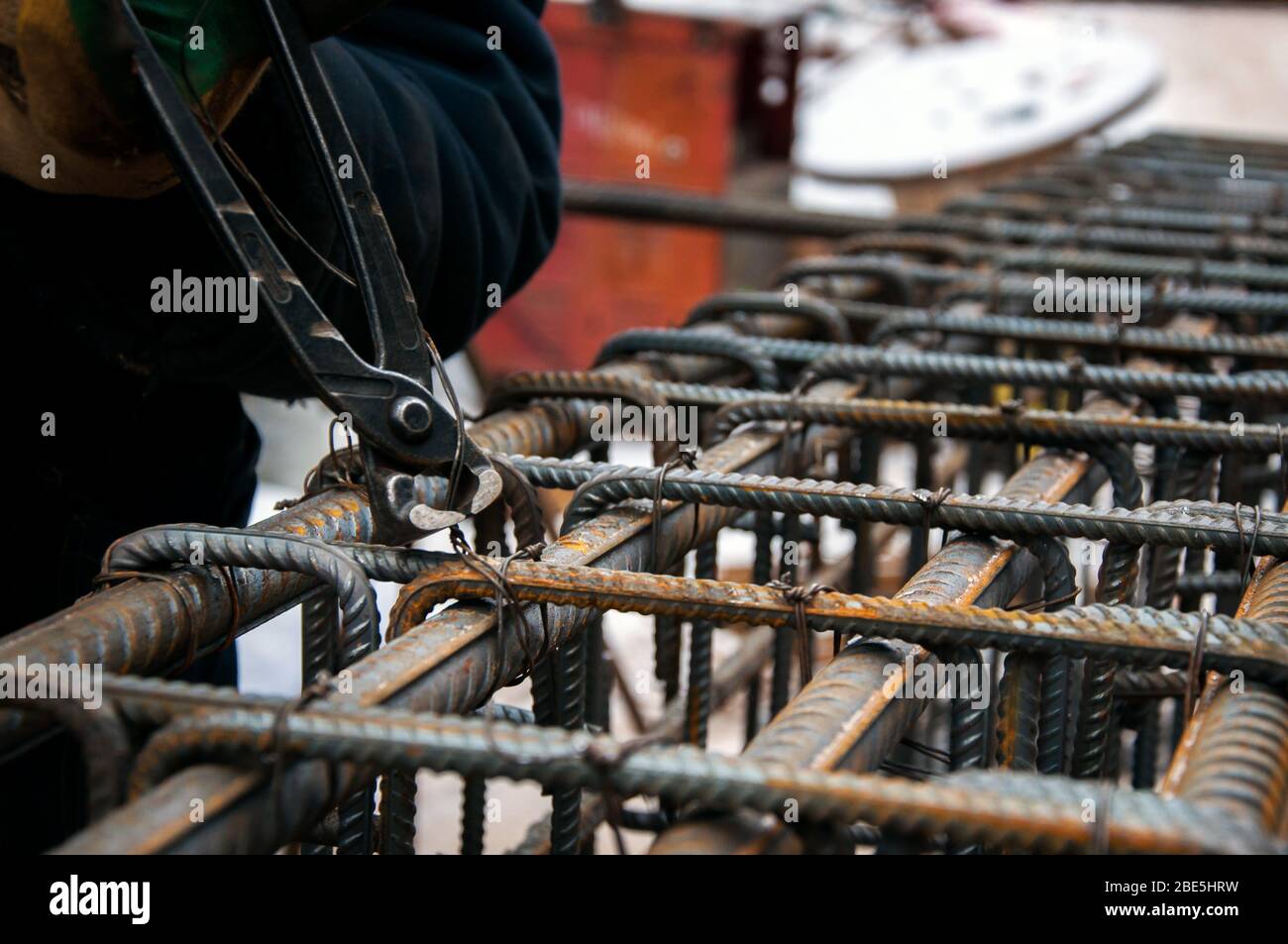 Fissaggio delle barre di riposizionamento l'una all'altra. Le mani del lavoratore fissano il rinforzo con il filo. Foto Stock