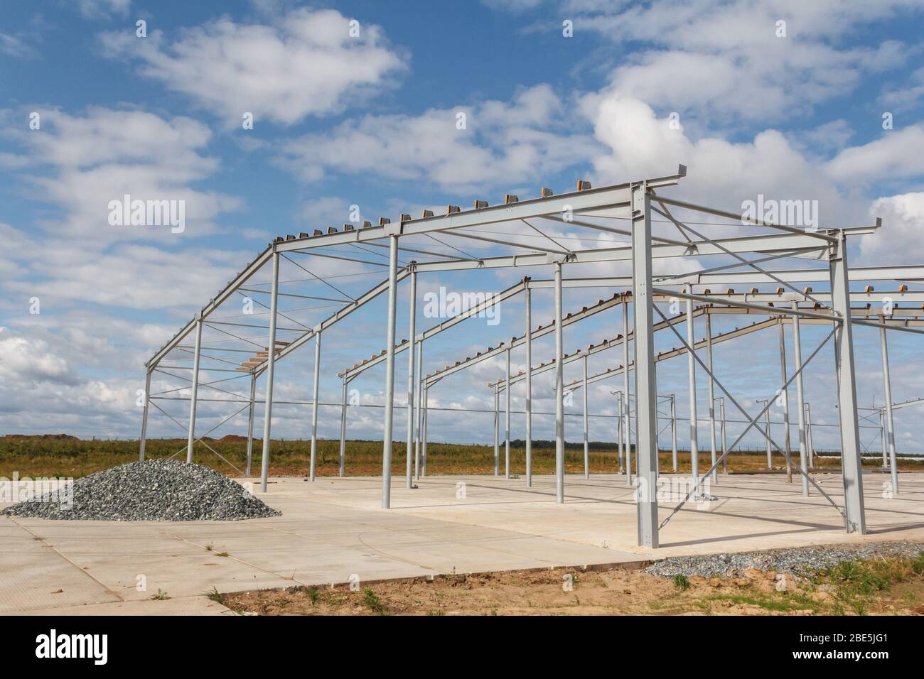 Struttura in acciaio su un nuovo edificio contro il cielo blu con nuvole. Costruzione rapida Foto Stock