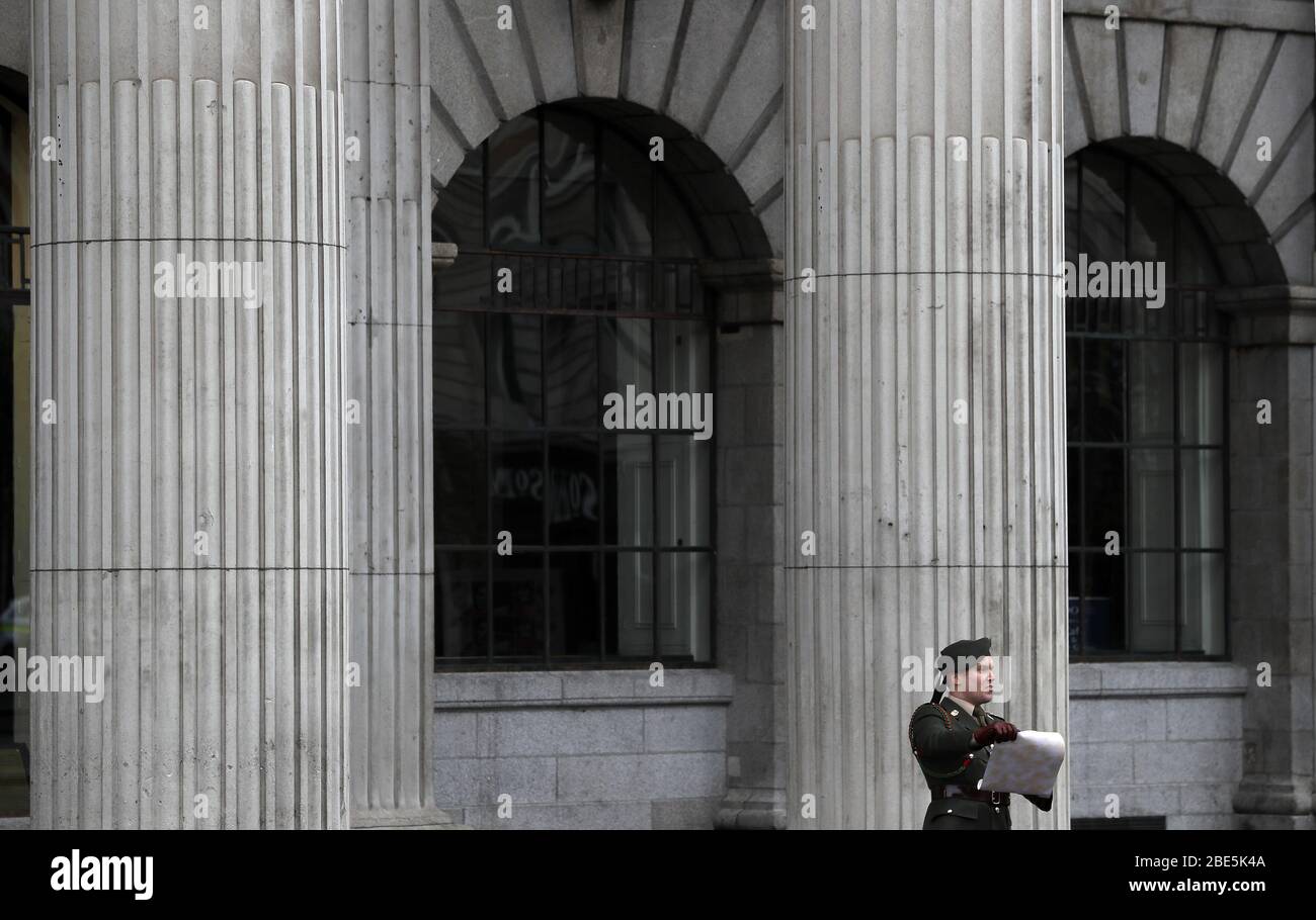 Il Capt. Darren Reilly delle forze di difesa irlandesi legge una copia dell'annuncio fuori dall'OGP sulla o'Connell Street di Dublino durante l'annuale Commemorazione pasquale del 1916, che a causa del coronavirus si è tenuto nel cortile interno dell'edificio. Foto Stock