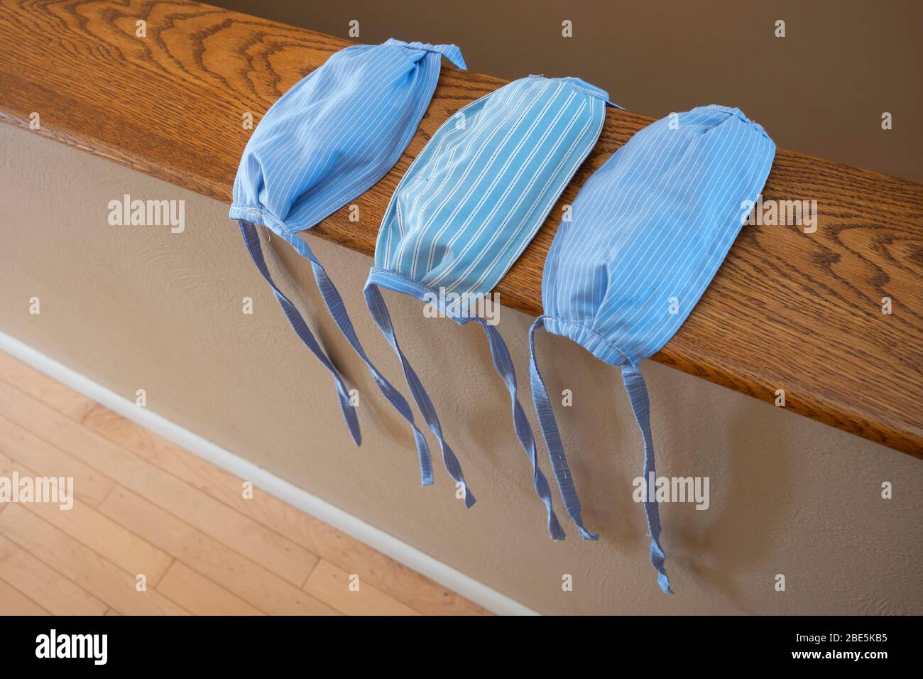 Un primo piano di tre maschere facciali cucite a mano realizzate in tessuto di cotone a strisce blu, senza fasce elastiche, per evitare la diffusione del COVI Foto Stock