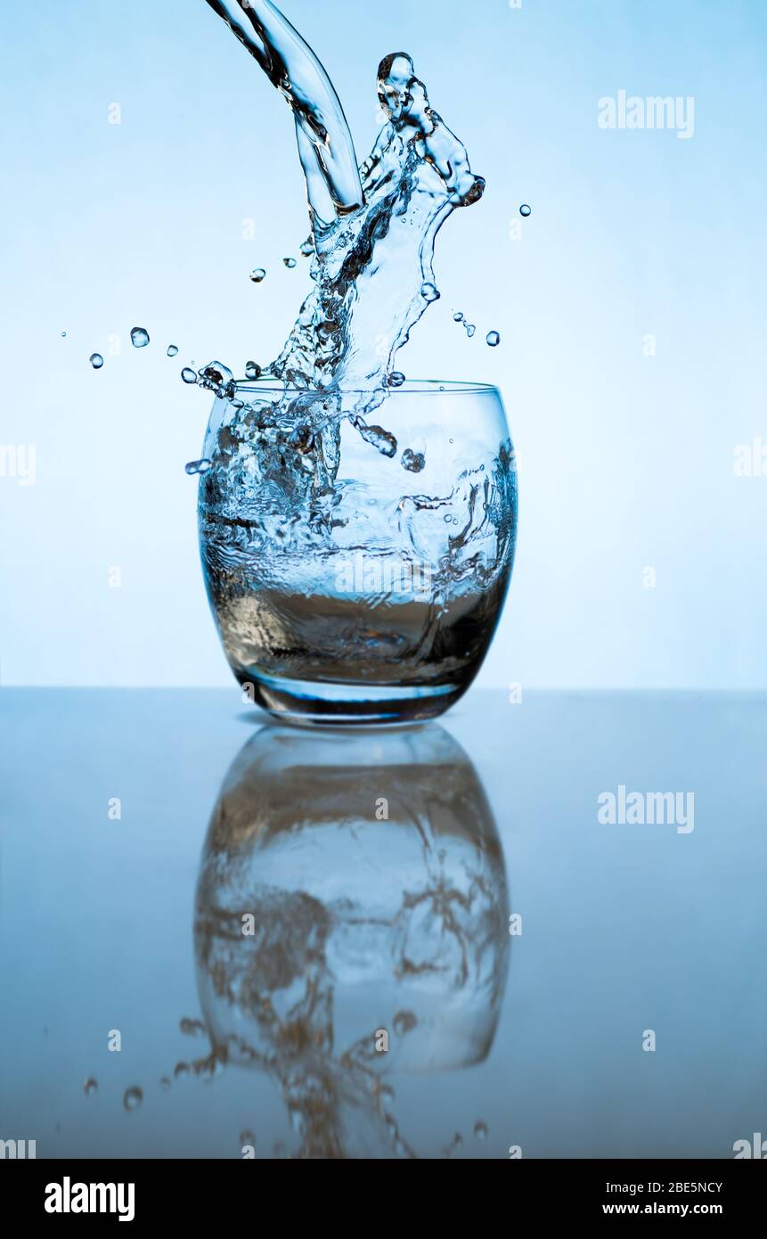 Acqua che si versa in un bicchiere e spruzzi fuori Foto Stock
