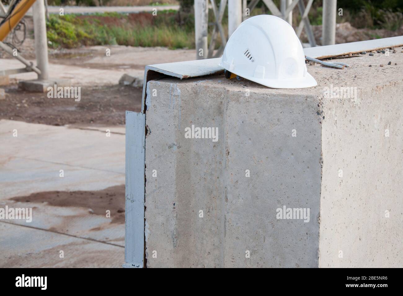 Cappello da costruzione bianco su una lastra di cemento. Protezione del  capo. Proteggere una persona in un cantiere Foto stock - Alamy