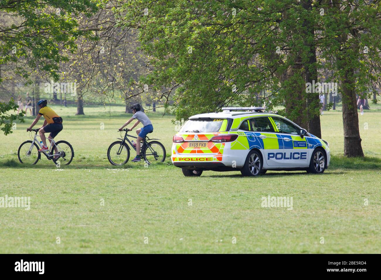 Londra, UK, 12 aprile 2020: La domenica di Pasqua un'auto della polizia guida lentamente per garantire che le persone osservino le regole di distanza sociale mentre si esercitano e si respirano aria fresca al sole su Clapham Common. Anna Watson/Alamy Live News Foto Stock