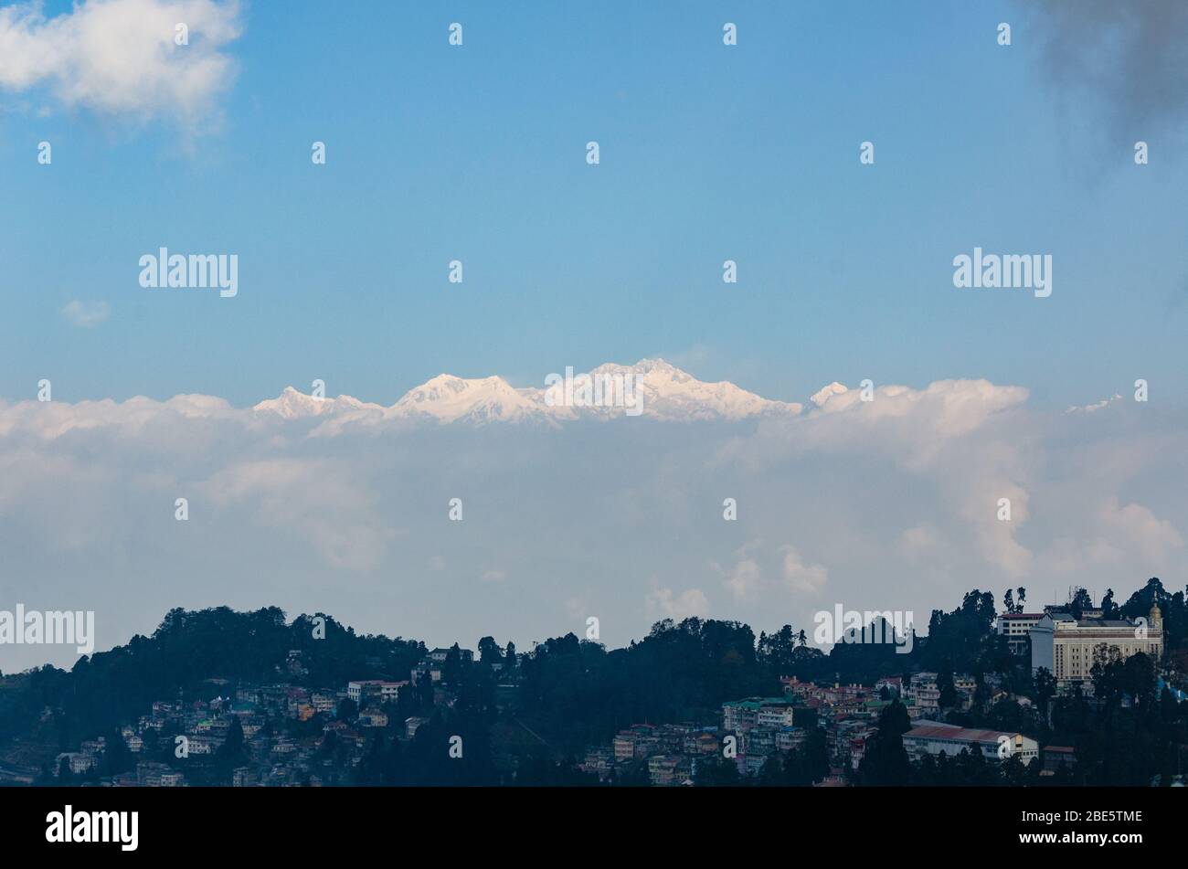 Bella vista del massiccio di Kangchenjunga che sorge su basse nuvole giacciono su una mattina invernale parzialmente nuvolosa a Darjeeling, Bengala Occidentale, India Foto Stock