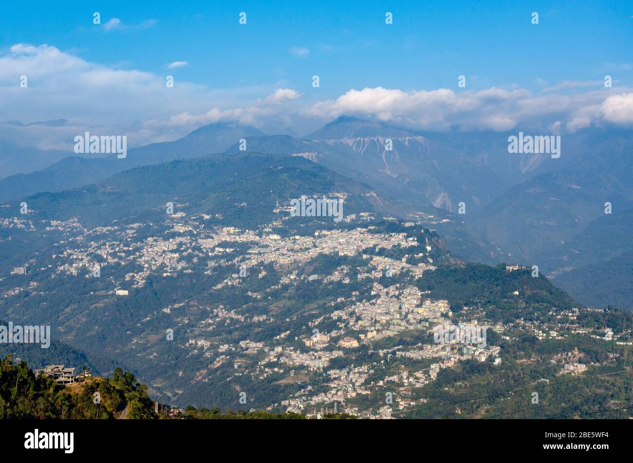 Vista del gruppo di case della città di Gangtok accoccolato sul pendio di montagna come visto dal monastero di Rumtek, Sikkim, India Foto Stock
