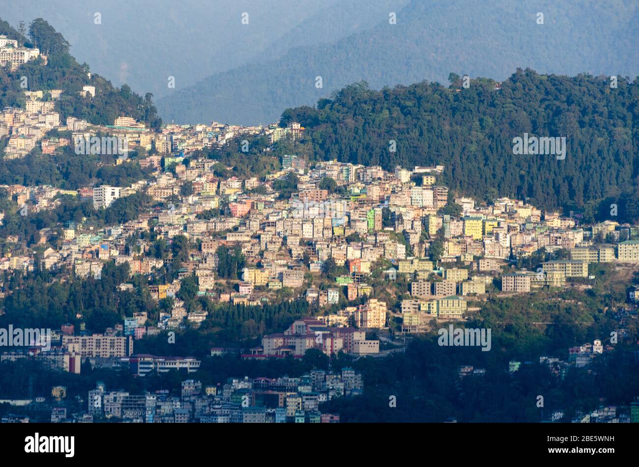 Vista del gruppo di case della città di Gangtok accoccolato sul pendio di montagna come visto da qualche parte vicino al monastero di Rumtek, Sikkim, India Foto Stock