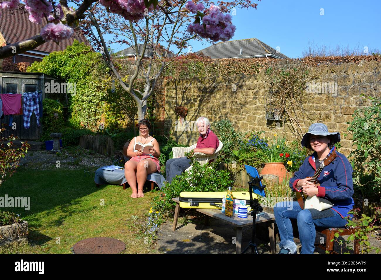 Gruppo familiare godendo il giardino nella primavera, rimanere a casa, stare al sicuro, durante la pandemia Covid-19 Foto Stock
