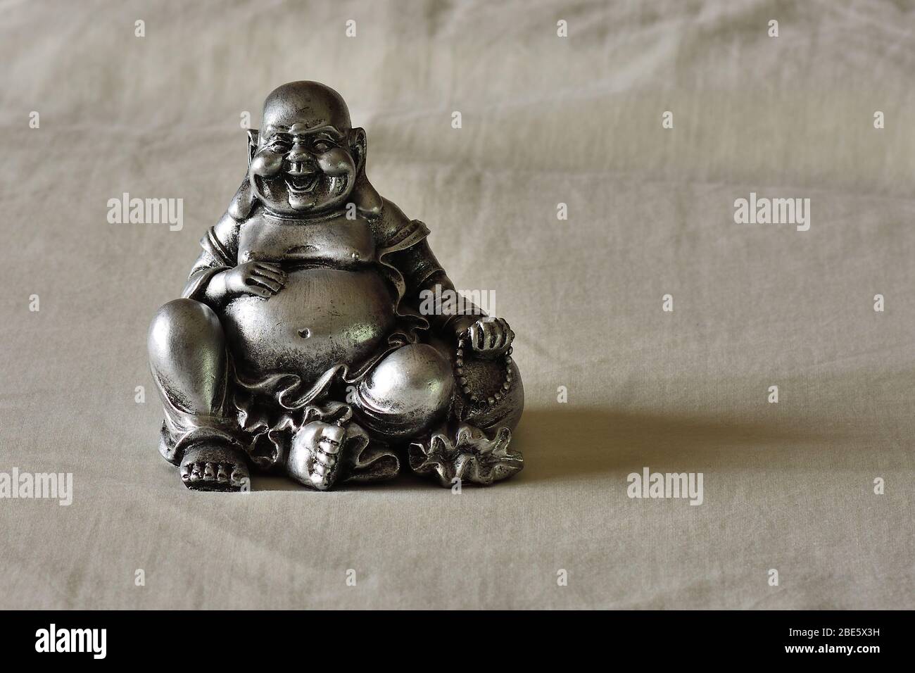Buddha sorridente su sfondo di stoffa Foto Stock