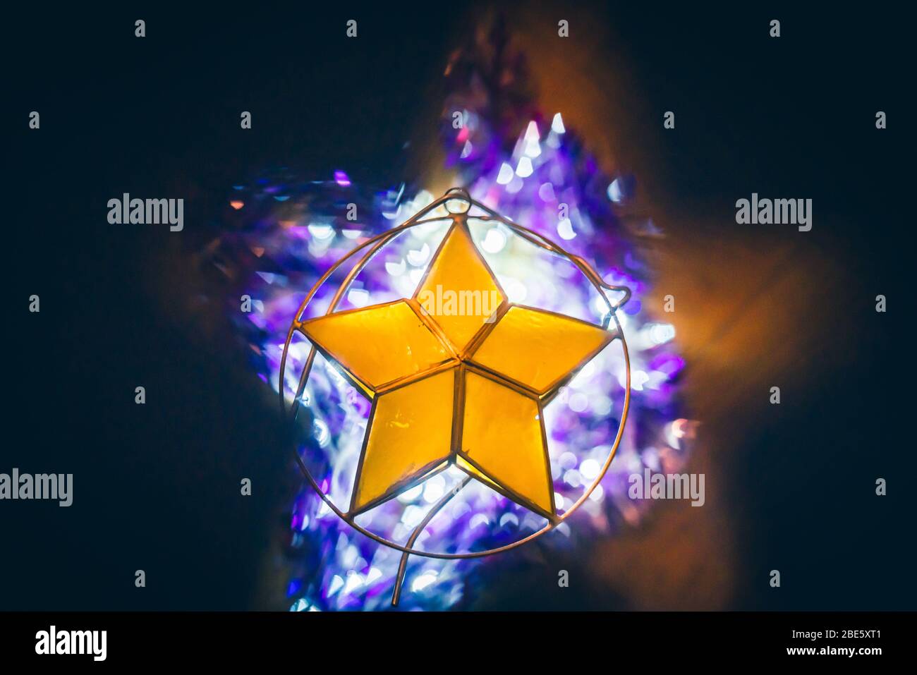 Decorazioni natalizie: Ornamento giallo Stella per albero di Natale con luci bianche e Boas viola Foto Stock
