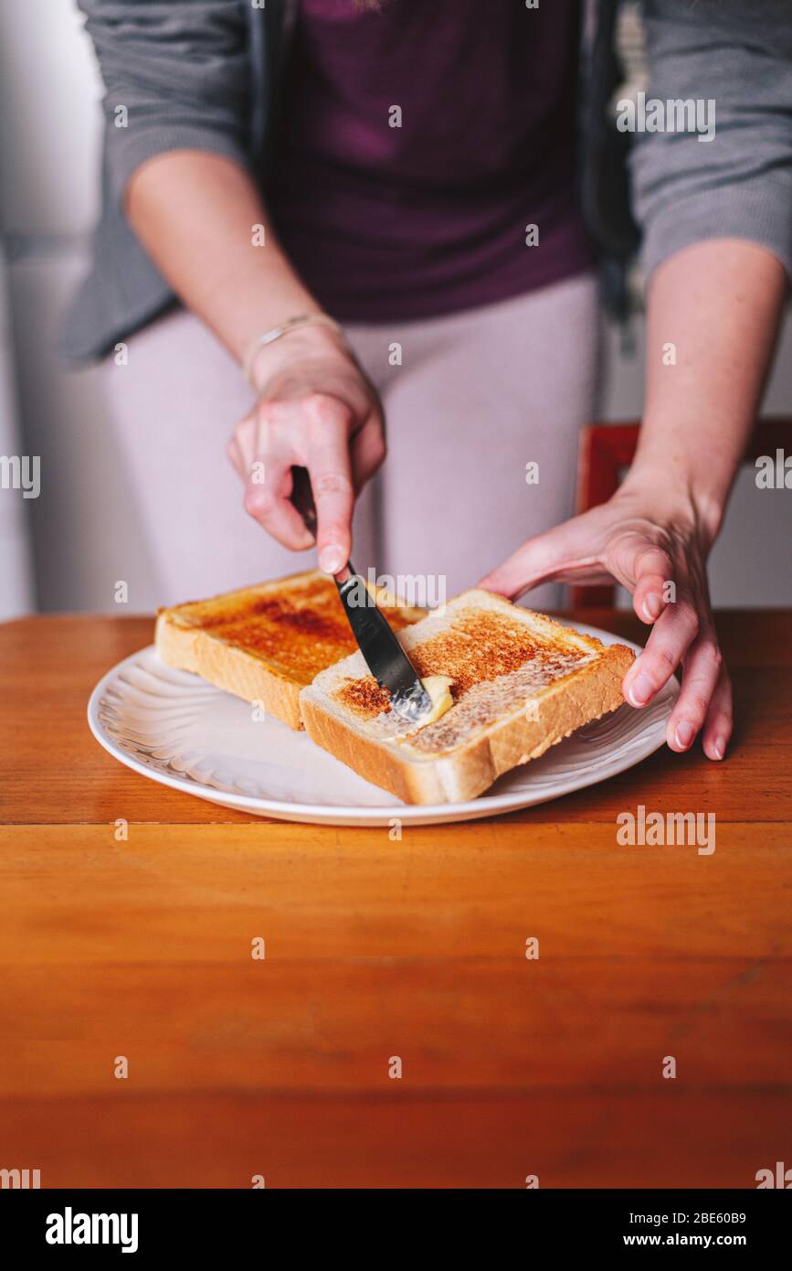 due mani spalmare il burro sul pane tostato Foto Stock