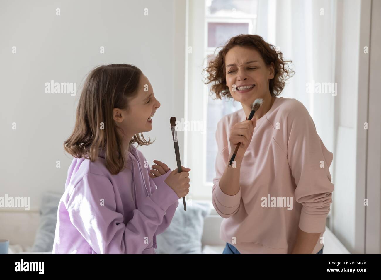 Mamma felice e figlia teen divertirsi cantando in pennelli Foto Stock
