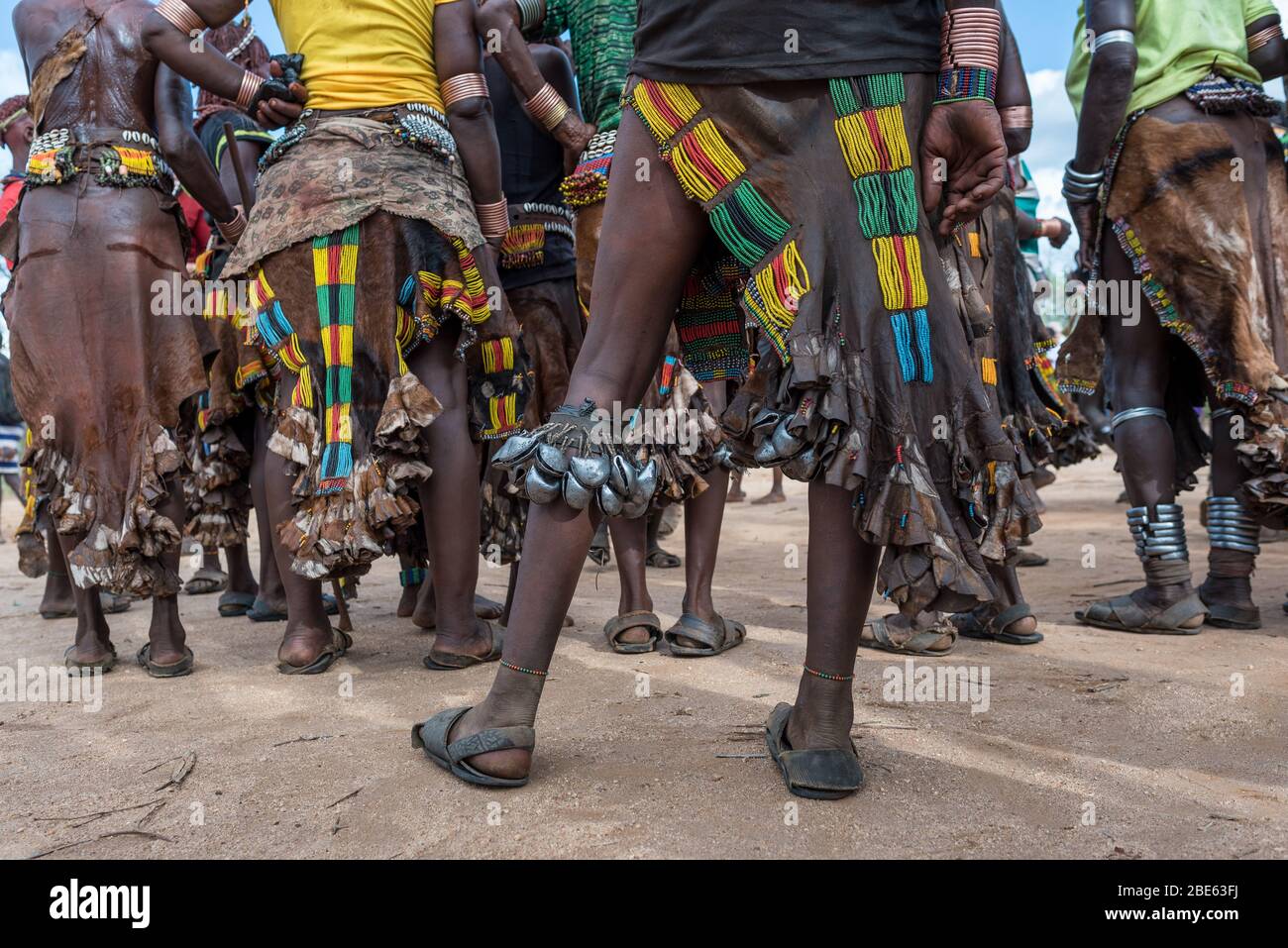 Ballerini con campane sulle gambe a Mursi tribù etnico gruppo venuta di età bull jumping cerimonia, Jenka, Etiopia, Foto Stock