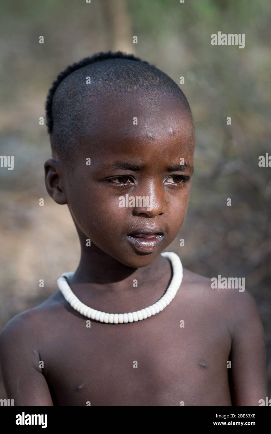 Giovane ragazzo con collana di perle è spettatore a Mursi tribù etnico gruppo venuta di età bull jumping cerimonia, Jenka, Etiopia, Foto Stock