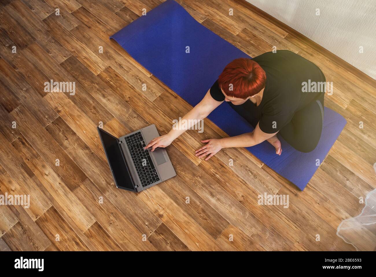 La ragazza adulta pratica lezione di yoga online a casa durante l'isolamento quarantena durante la pandemia di coronavirus. Foto Stock
