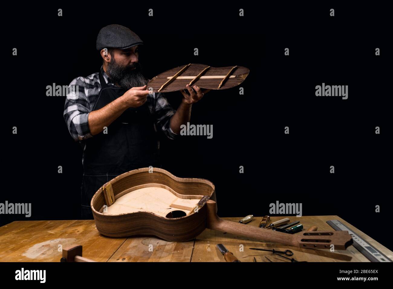 Il più basso posteriore di misurazione della chitarra spagnola. Chitarra da banco in costruzione. Sfondo nero scuro. Foto Stock