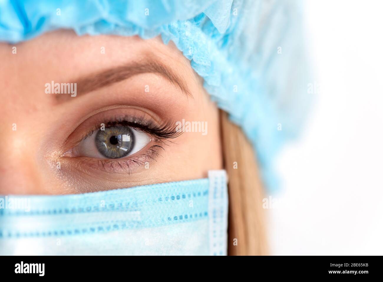 Chiudere l'occhio di un medico chirurgo femminile adulto che indossa la maschera protettiva e il cappuccio. Assistenza sanitaria, assistenza medica di emergenza e concetto di chirurgia Foto Stock