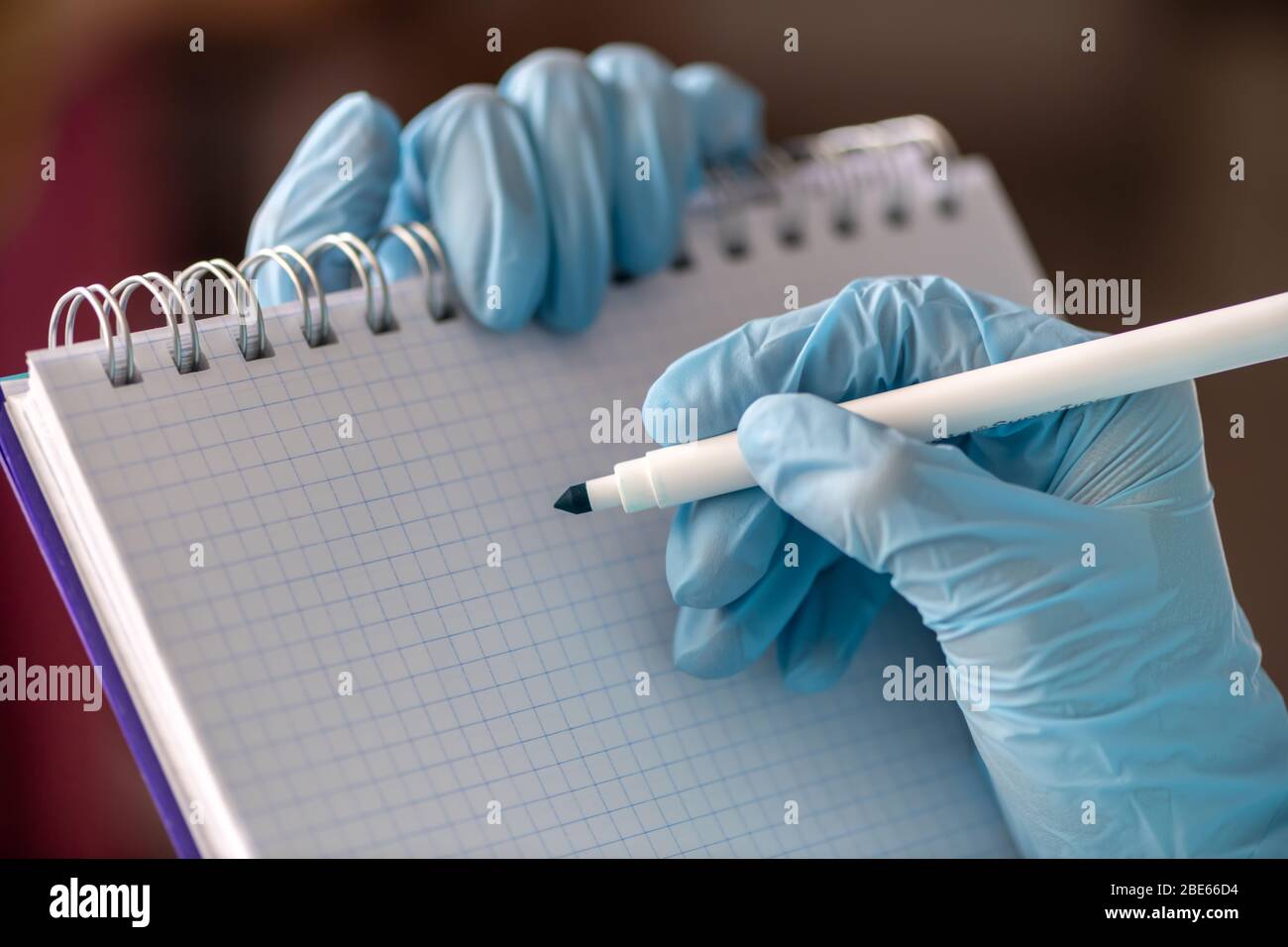 La mano femminile in un guanto per uso medico contiene una compressa per la scrittura e una penna. Concetto di medicina Foto Stock