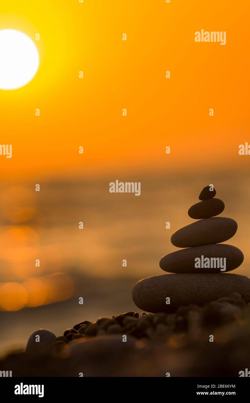 Piramide piegata Zen pietre ghiaia sul mare spiaggia al tramonto Foto Stock