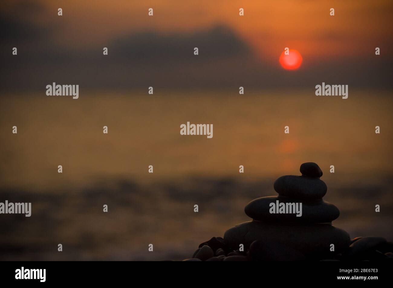 Piramide piegata Zen pietre ghiaia sul mare spiaggia al tramonto Foto Stock