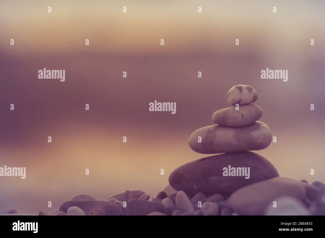 Piramide piegata Zen pietre ghiaia sul mare spiaggia al tramonto Foto Stock