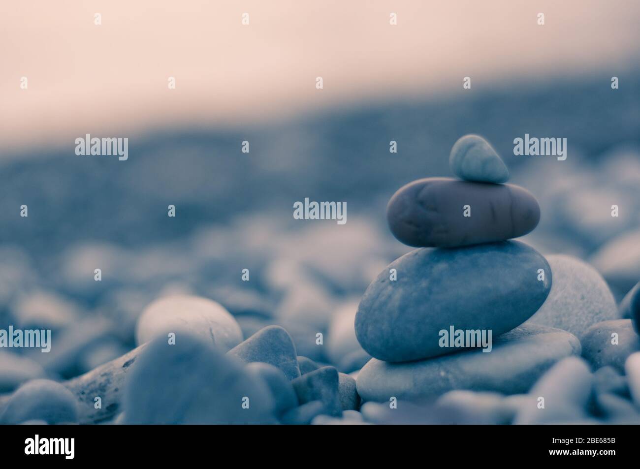 Piramide piegata Zen pietre ghiaia sul mare spiaggia al tramonto Foto Stock