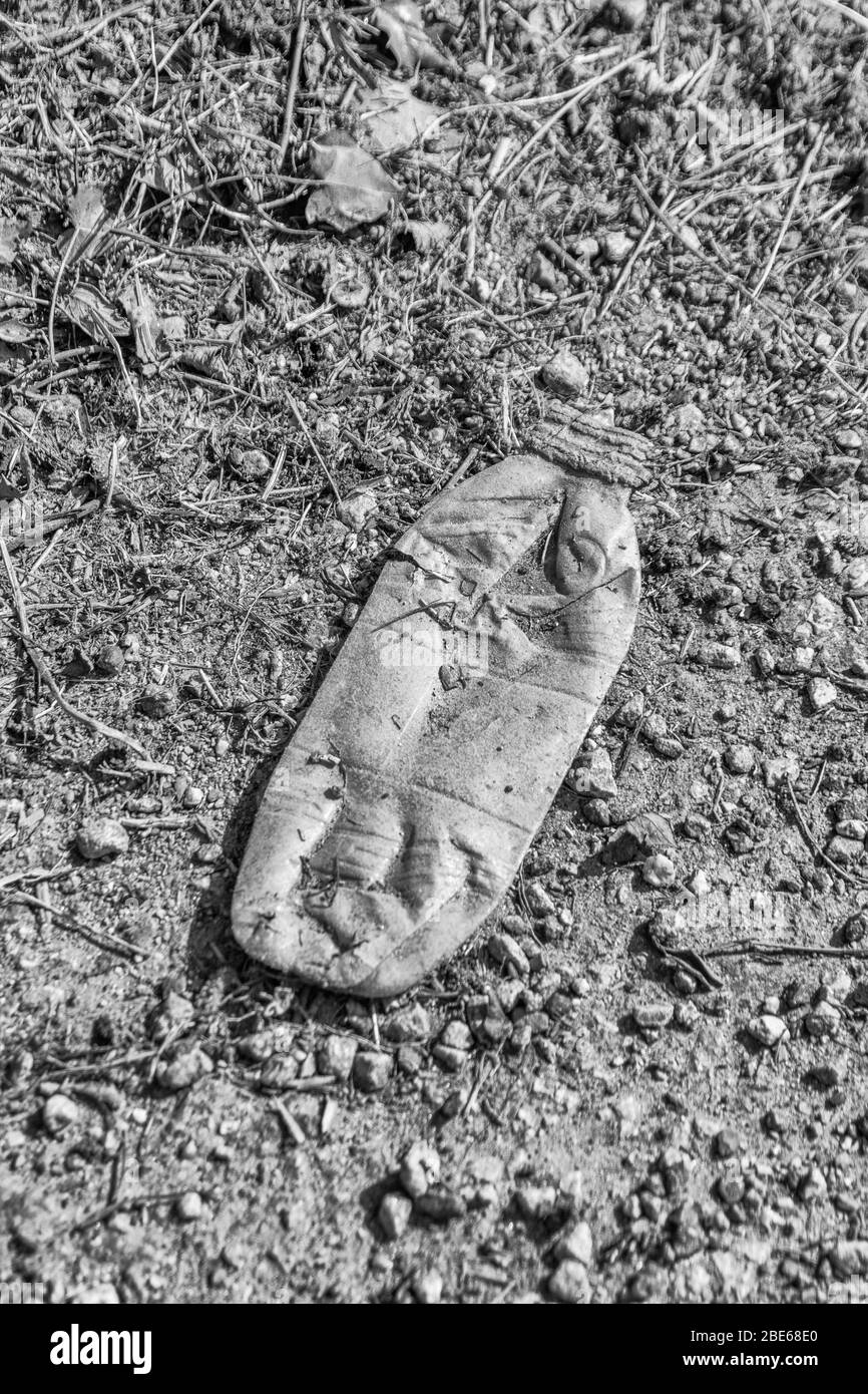 Bottiglia di bibite analcoliche B&W sul asfalto di una tranquilla strada di campagna. Esempio di inquinamento della plastica nelle campagne britanniche, rifiuti di plastica monouso, rifiuti di plastica Foto Stock