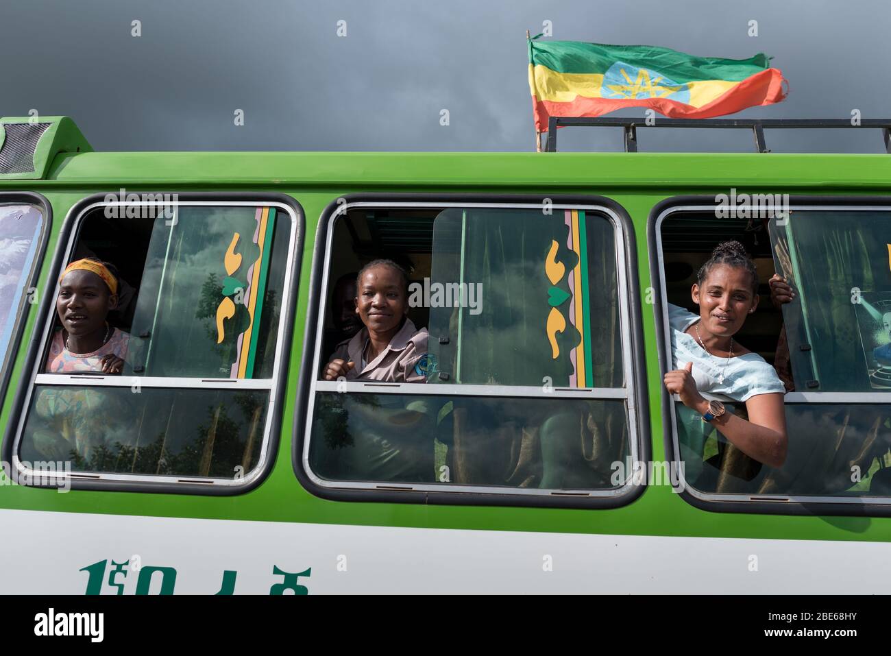 Gli studenti delle scuole si ondano e si rallegrano dalle finestre degli autobus mentre la processione degli studenti arriva a Jenka per iniziare il nuovo mandato scolastico, Jenka, Etiopia, Africa. Foto Stock