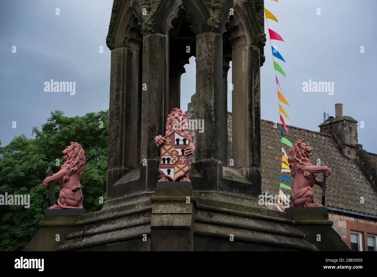 Vista parziale delle tre statue di leoni rosa che tengono le creste in cima alla fontana di Bruce, Falkland, Fife, Scozia, Regno Unito, Europa Foto Stock