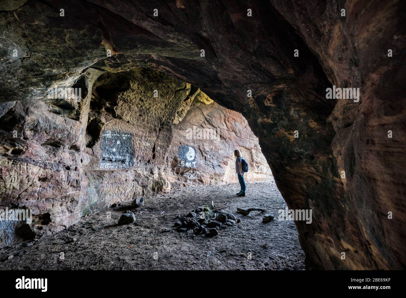 Una turista femminile esplora le grotte di Caiplie, o calette, formazioni rocciose lungo il Mare del Nord sul Fife Coastal Path, Crail, Scozia, Europa Foto Stock