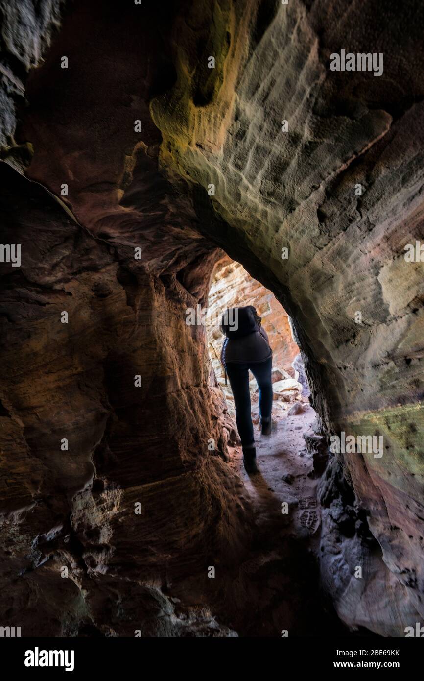 Una turista femminile esplora le grotte di Caiplie, o calette, formazioni rocciose lungo il Mare del Nord sul Fife Coastal Path, Crail, Scozia, Europa Foto Stock