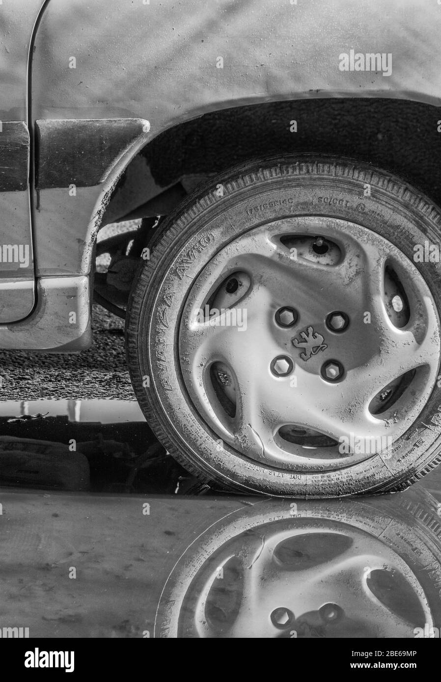 Grintoso bianco e nero di ruota / pneumatico e passaruota di una vettura Peugeot, con logo Peugeot marquelion visibile su berretto. HDI ma modello preciso sconosciuto. Foto Stock