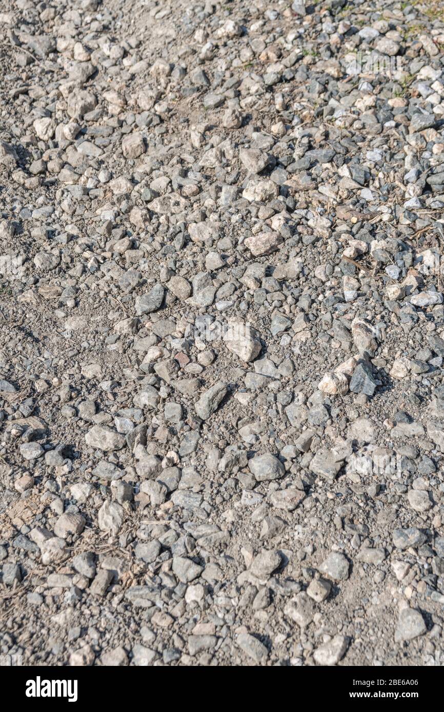 Soleggiato pietra / ghiaia hardcore su pista o sentiero di campagna. La metafora cade su terreni rocciosi, superfici ruvide, terreni accidentati, guida irregolare, superfici irregolari. Foto Stock
