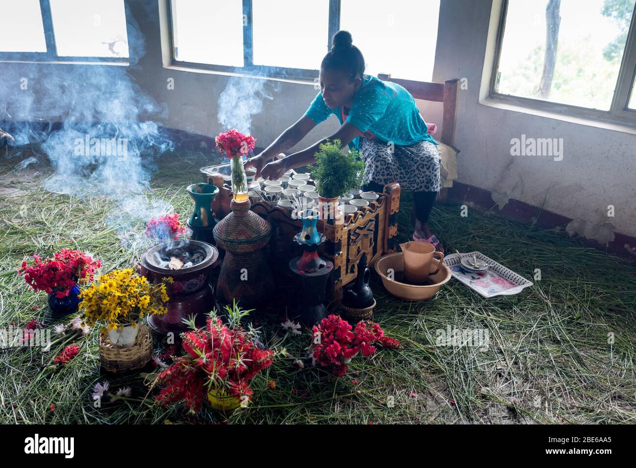 Una giovane donna prepara il caffè per gli ospiti del ristorante, mentre l'incenso brucia tra i fiori, Addis Abeba, Etiopia. Foto Stock