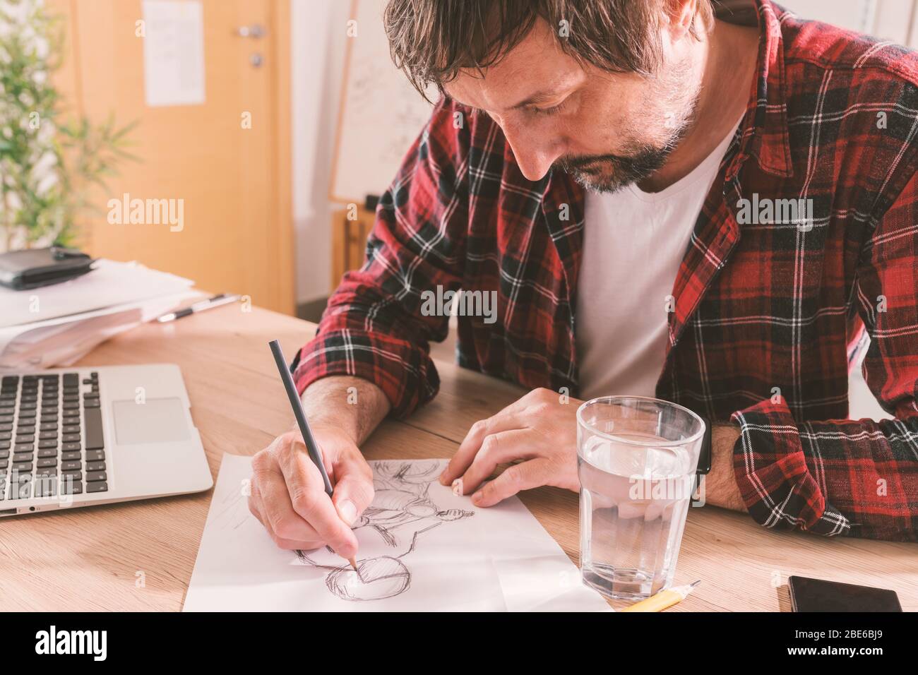 Illustrator a mano libera disegnando motociclista con matita, fuoco selettivo Foto Stock