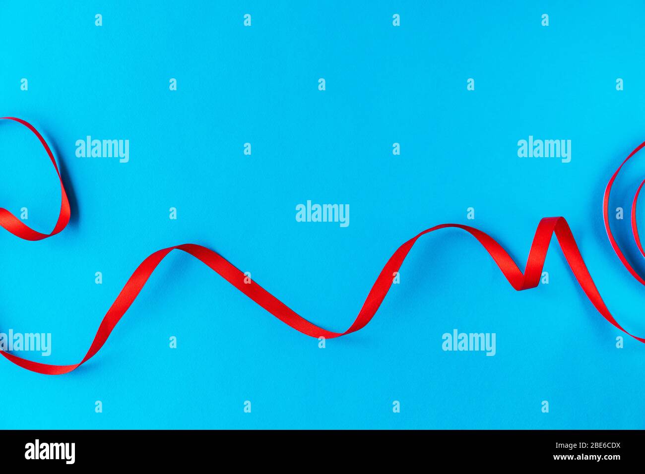 Nastro rosso ondulato su sfondo blu. Una buona idea per una carta di vacanza o sfondo per il testo, come uno sfondo per computer o uno screensaver sul telefono Foto Stock