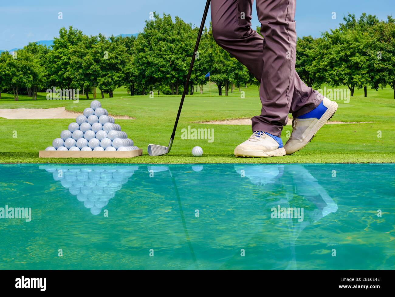 Giocatore di golf che pratica in un campo di guida con la piramide delle palle di golf Foto Stock