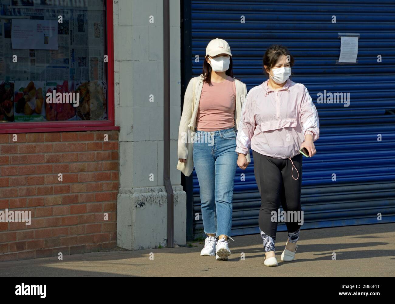 Due donne fuori camminare, indossando maschere facciali, durante il blocco del virus Corona Foto Stock