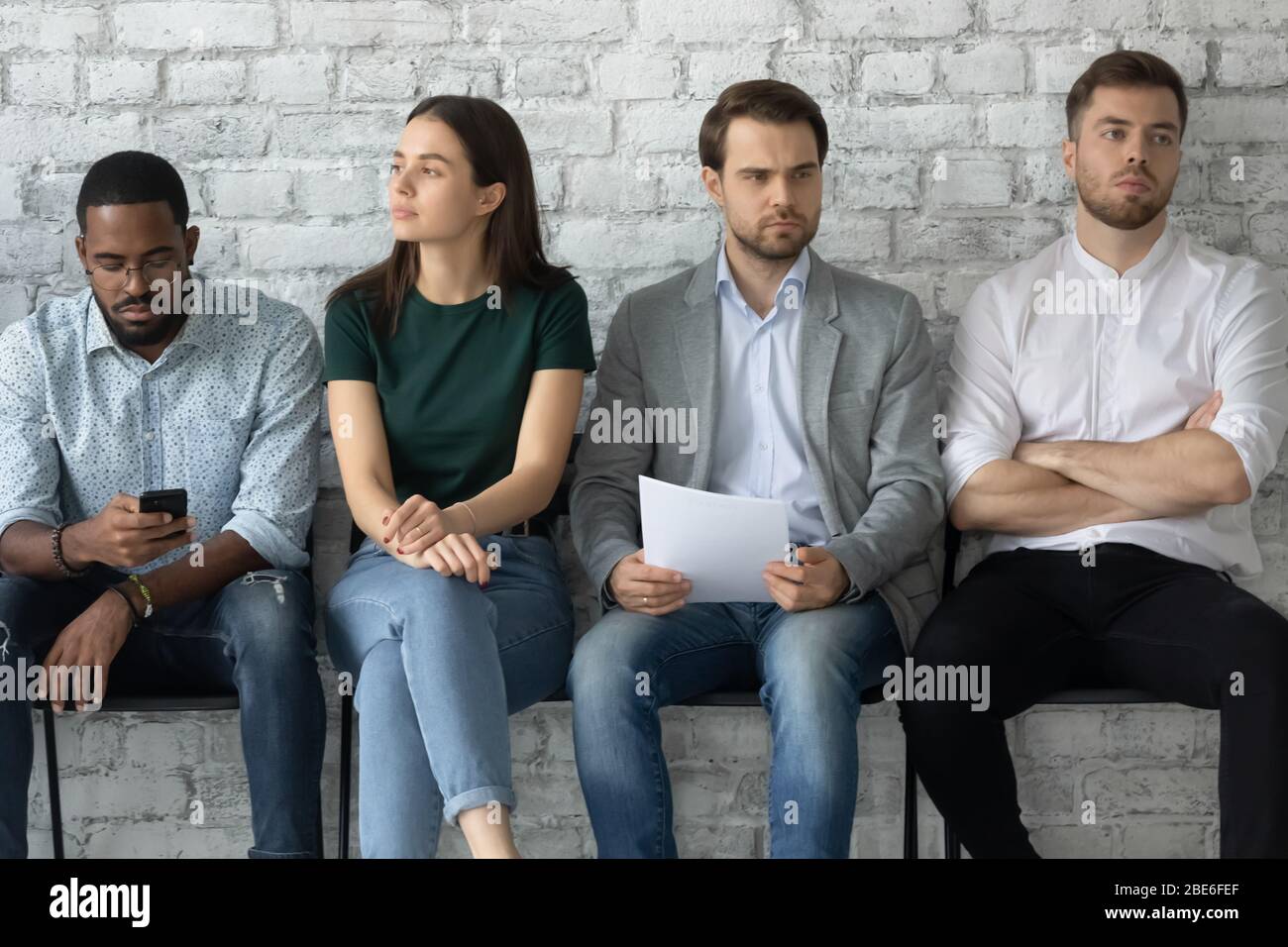 Giovane candidato multirazziale sentirsi annoiato prima dell'intervista in ufficio Foto Stock
