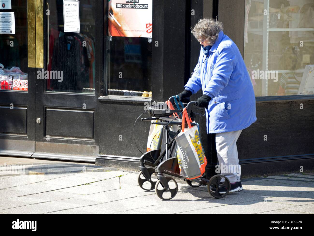 Vecchia signora, con aiuto a piedi, fuori shopping durante il blocco del virus Corona Foto Stock