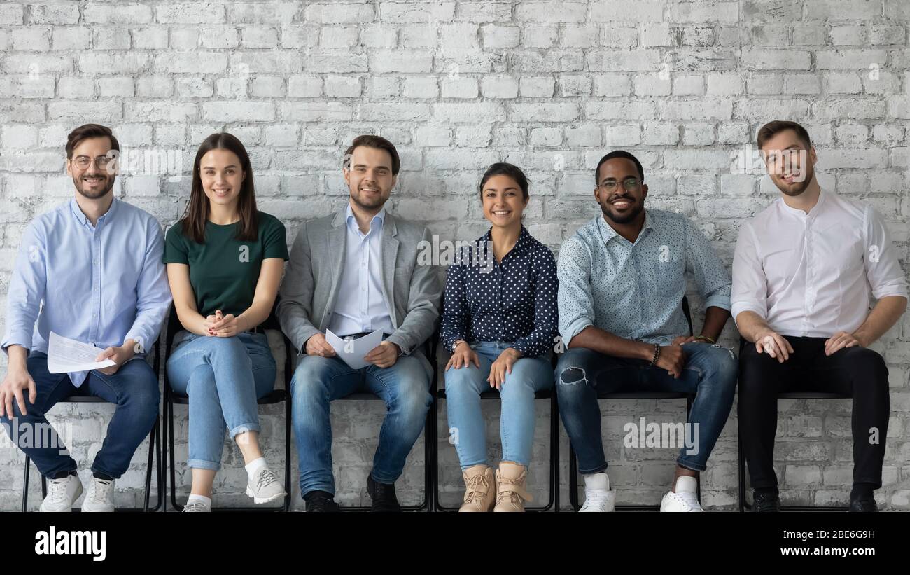 Ritratto di candidati multirazziali felici sedersi in fila in corridoio Foto Stock